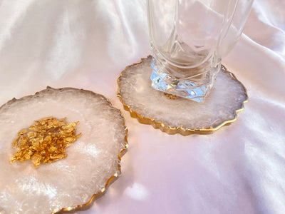 Handmade Pearlescent White and Gold Crushed Glass Elegant Large Resin Geode Coasters with Gold Accented Rim Edges - Jasmin Renee Art - Two Coasters with Glass Cup on Table